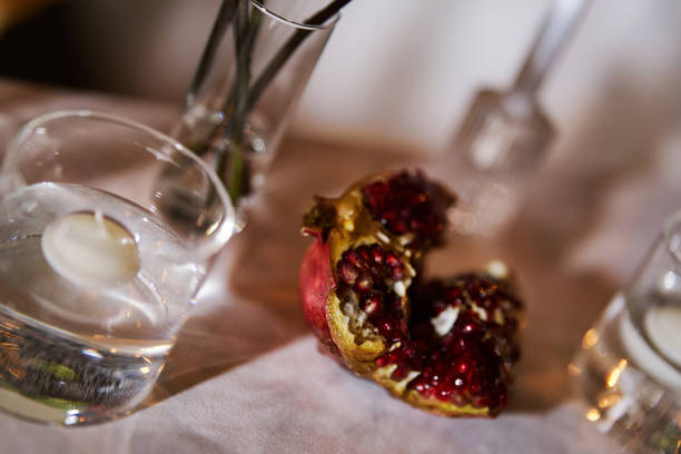 A decorative table setting featuring a pomegranate, glasses of water, and elegant glassware in a cozy indoor environment