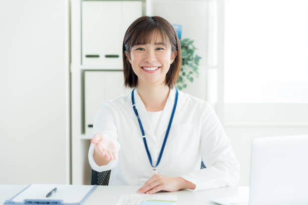 a receptionist woman wearing a white coat - 説明 ストックフォトと画像