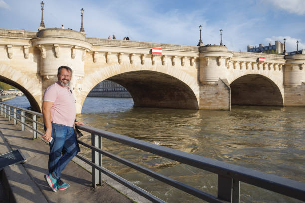 A sun-dappled Parisian bridge spans the Seine, showcasing intricate architecture and pedestrian activity.  The image evokes a tranquil yet vibrant mood, ideal for travel brochures, tourism websites, or historical documentaries.  Its detailed composition offers high-resolution potential for various commercial applications.