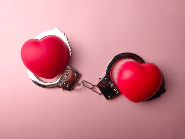 istock Top view metal handcuff and red heart shaped on a pink background 2184285423