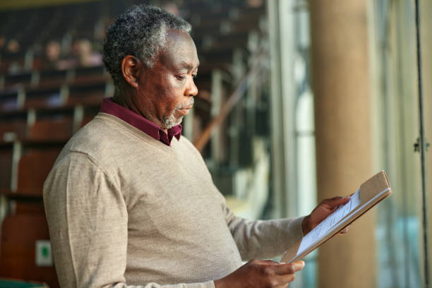 istock Senior black professor reading exams in lecture hall. 2184291309