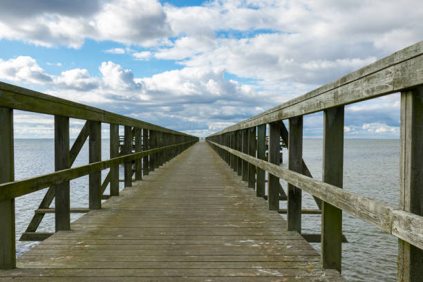 istock Wooden pier extends into calm waters under a cloudy sky during the afternoon, inviting exploration and tranquility 2184291971