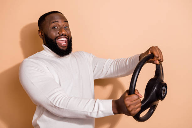 istock Photo of cheerful positive young guy dressed white pullover riding automobile isolated beige color background 2184296667