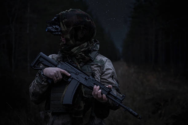 istock A special forces soldier with an assault rifle in camouflage and with a night vision device in a dark forest. 2184299954