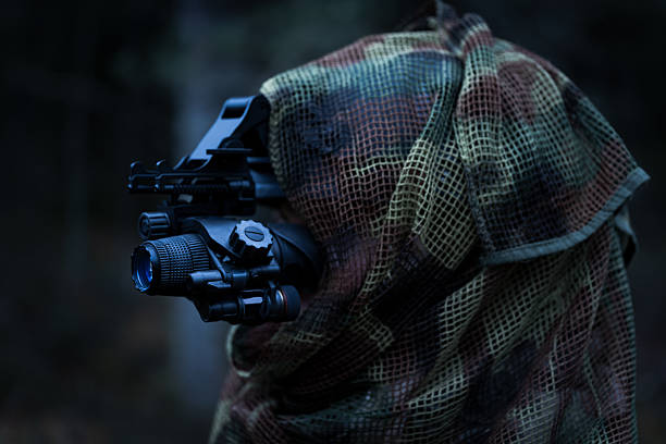 istock A reconnaissance soldier in camouflage and with a night vision device in a dark forest. 2184300021
