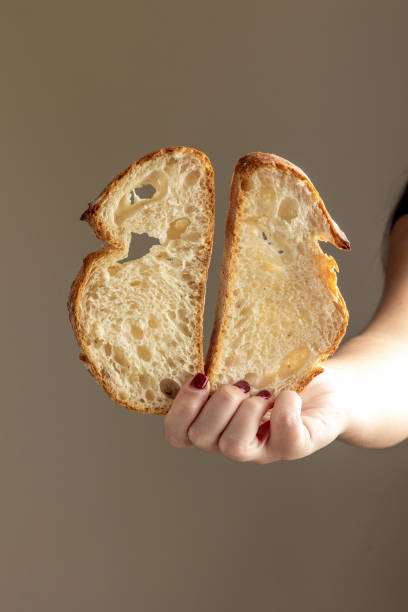 istock Slice of sourdough bread held by hand against backdrop 2184300439