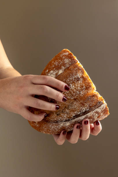 istock Slice of sourdough bread held by hand against backdrop 2184300477