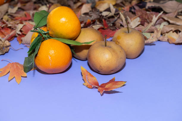 Delicious pears and tangerines with autumn leaves on the table.