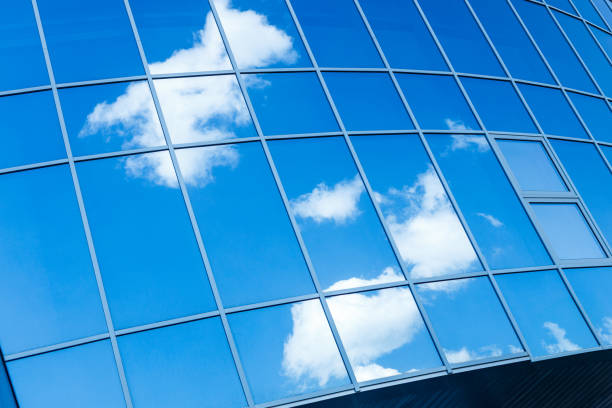 The mirrored large windows on the back are positioned diagonally in the frame. reflecting sky and clouds on a mirrored surface