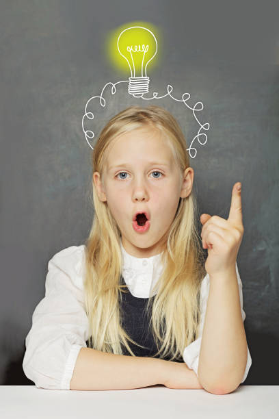 istock Funny child girl student with yellow light bulb on school blackboard background. Creativity, education and idea concept 2184306487