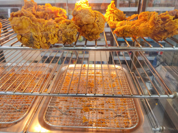 Crispy fried chicken displayed neatly in a convenience glass store's warmer.
