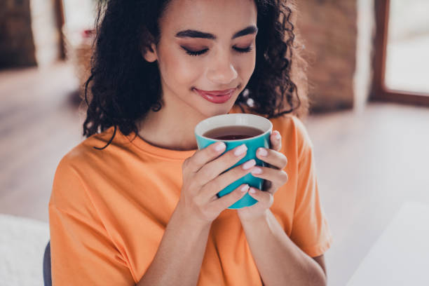 istock Young female student enjoying a warm drink in her cozy apartment while studying from home 2184308004