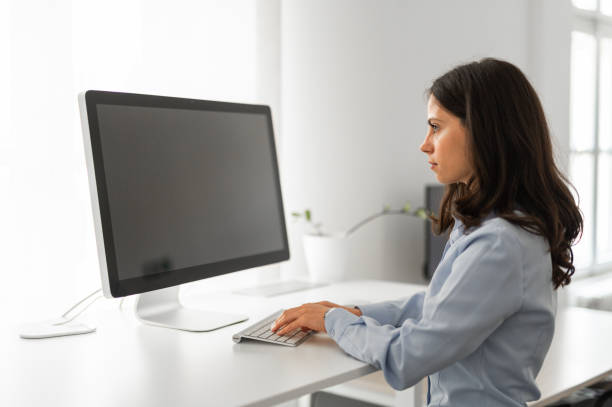 istock Smilling young attractive brunette working at her desk on computer, mockup screen, copy space 2184308512