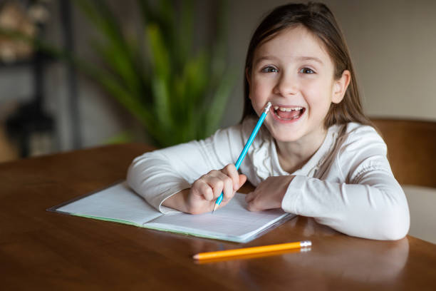 istock happy child writes with pencil in notebook at home at table. drawing or studying. girl doing homework 2184314966