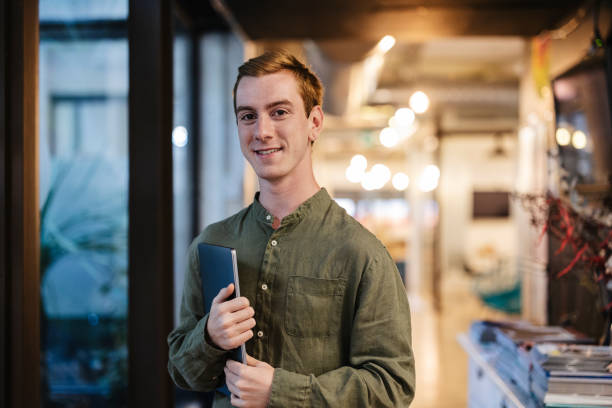 istock Young man holding tablet and smiling in coworking space 2184319149