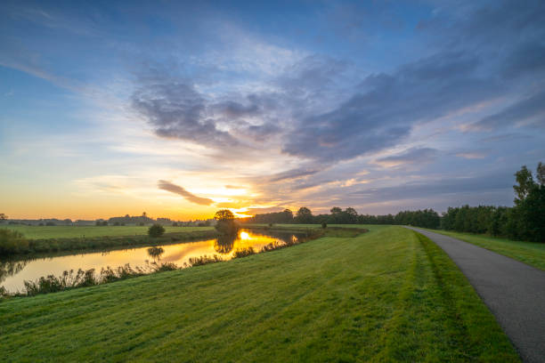 Sunrise over the Vecht river during a beautiful fall morning in Overijssel, The Netherlands. The Overijsselse Vecht originates in Oberdarfeld in the German state of North Rhine-Westphalia and flows north into Lower Saxony across the border into the Dutch province of Overijssel. There, it flows through the Salland region and close to the city of Zwolle, the river flows into the Zwarte Water river.