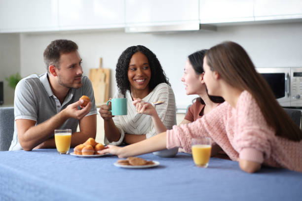 Happy interracial friends talking at breakfast in the kitchen
