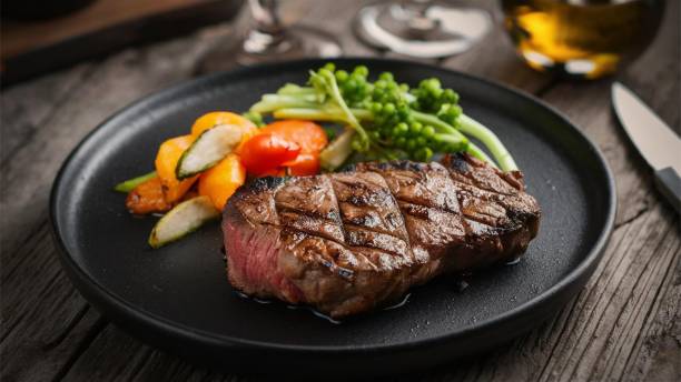 Grilled steak with vegetables on black plate