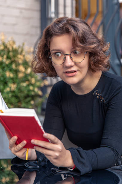 istock Surprised young woman reading a book. Emotion concept. Surprised emotion. 2184330357
