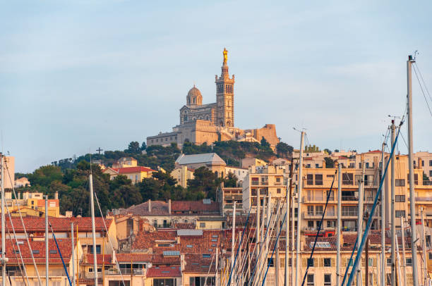 Marseille, France - July 22, 2010: Evening view of the Vieux-Port with boats docked and the historic Notre-Dame de la Garde basilica in the background.