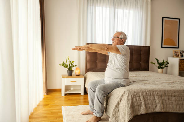 istock A senior man sitting on a bed in a bedroom and doing morning stretching exercises. 2184333045