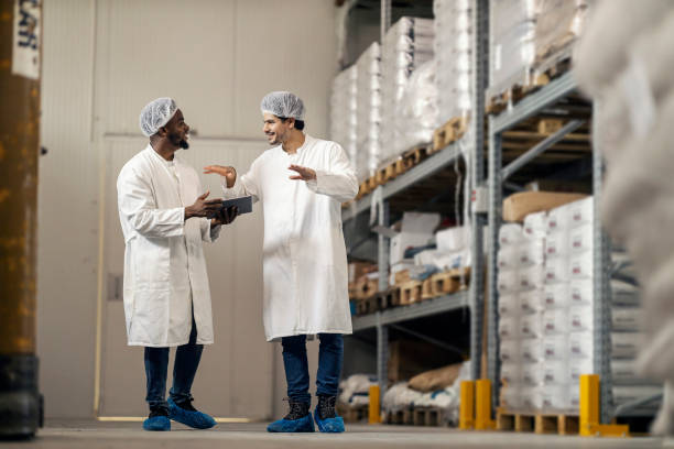 istock Black manager with tablet walking with his migrant storage worker and discussing shipment. 2184333435