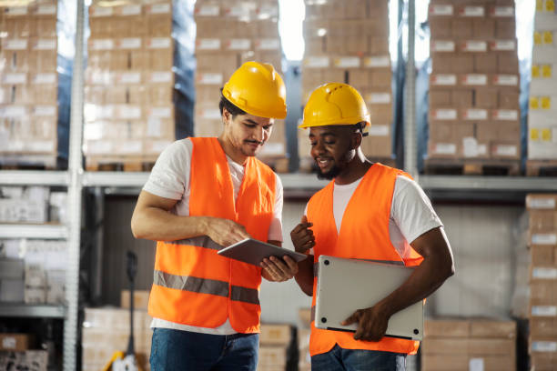 istock Interracial foreign industry employees standing at warehouse with tablet and laptop and planning logistic. 2184333632