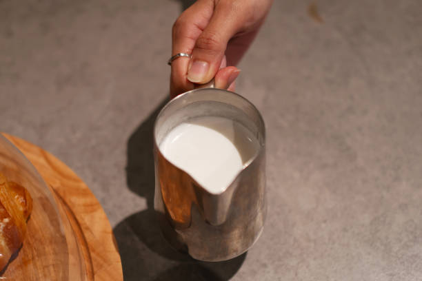 Hand holding a cup of steamed milk with foam.