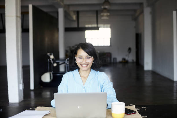 istock A young business woman glad at work smiling at laptop 2184337093
