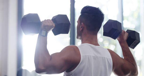 Fitness, man and weights with exercise in gym for strong muscles, biceps growth or workout performance. Athlete back, bodybuilder and weightlifting at sports center for endurance training or wellness
