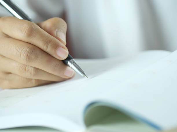 istock Hand holding pen writing on note paper. Finance business concept. Copy space. 2184337982