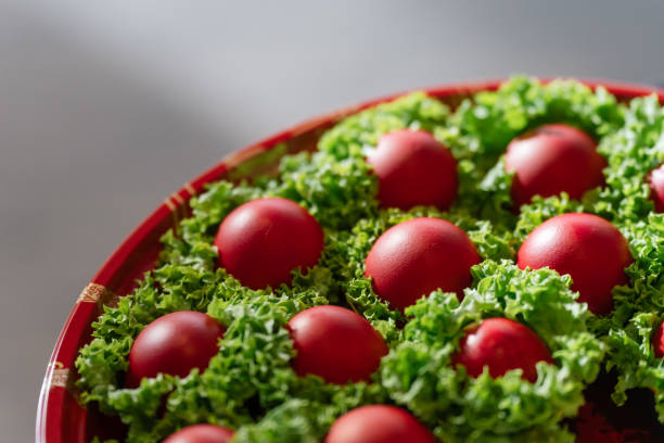 Red eggs displayed on a red tray, each nestled in lettuce for decoration.