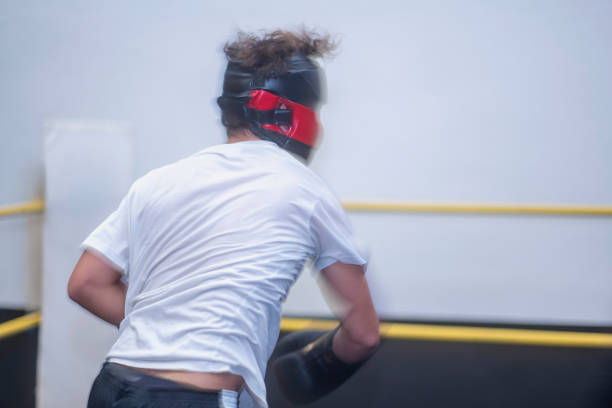 Boxer wearing a head guard and gloves throws a punch during training, demonstrating dedication and athleticism in the boxing ring