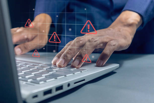 istock Man working on laptop with red triangle caution warning sign on virtual screen for notification error, restricted content or maintenance concept 2184345865