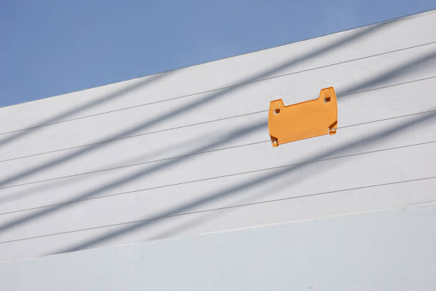 a yellow sign on electric wire security fence with home background.