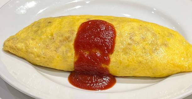 istock Omurice, a delightful Japanese dish with fluffy omelette wrapped around savory fried rice and topped with ketchup. Perfect for food photography, showcasing comfort food at its best. 2184346886