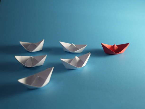 istock Leadership concept. Red paper boat navigation among white on blue background 2184352852