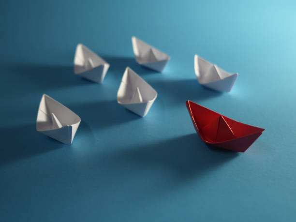 istock Creative idea. Red paper boat navigates among white on blue background 2184352961