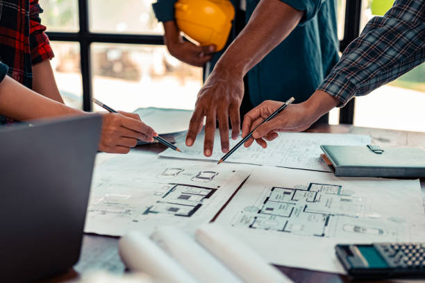 istock A team of architects plans and verifies home designs and home models. Architect designs working drawings, plans, blueprints, close-up images. 2184353758