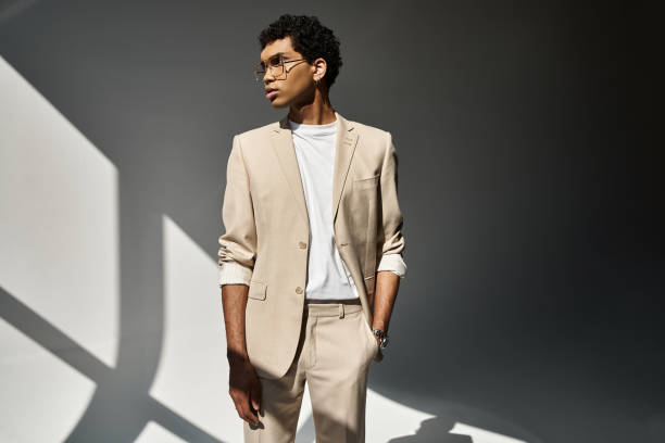 Stylish man in beige suit posing artfully in soft light against a modern backdrop
