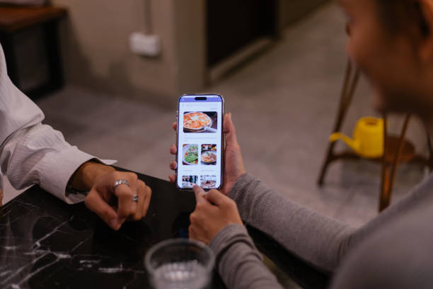 istock Close Up Friends Using Smartphone App To Order In Cafe 2184366063