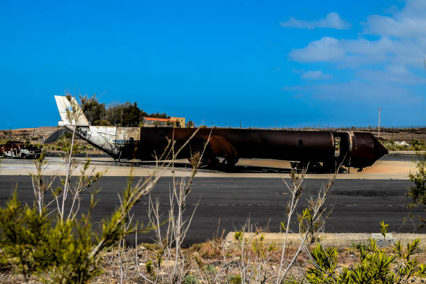A large airplane is sitting on the tarmac, with its wings and tail missing. The scene is desolate and abandoned, with no signs of life or activity