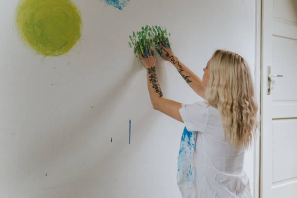 istock Tattooed Woman Applying Green Paint on Wall with Hands 2184374835