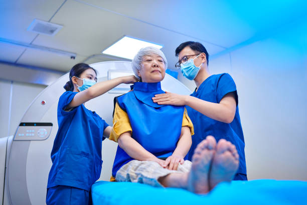 istock Two Nurses Assist Patient Putting on Radiation Protection Suit at MRI Scan 2184376062
