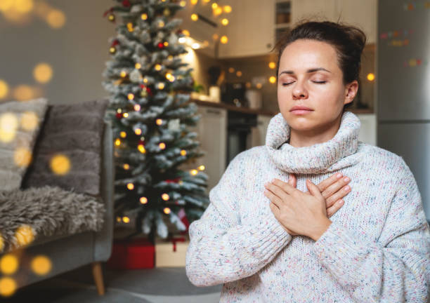 istock Woman in a warm knit sweater meditating and practicing breathing exercises at home during Christmas holidays. 2184377791