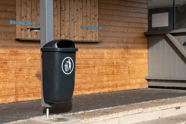 istock Black trash bin positioned near a wooden wall in a public area 2184378701