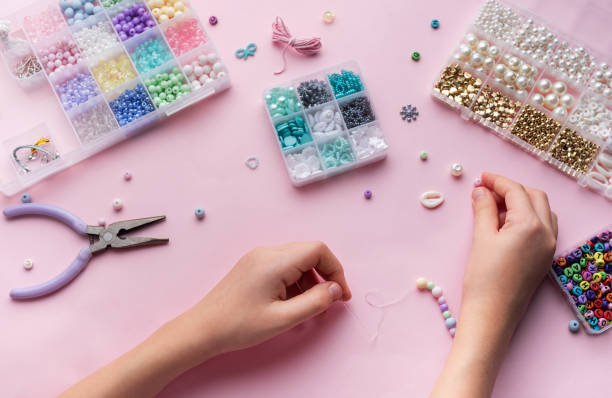 istock Crafting colorful jewelry with beads on a pastel workspace featuring tools and various materials 2184379807