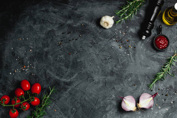 Black stone cooking background. Spices and vegetables. Top view. Free space for your text.