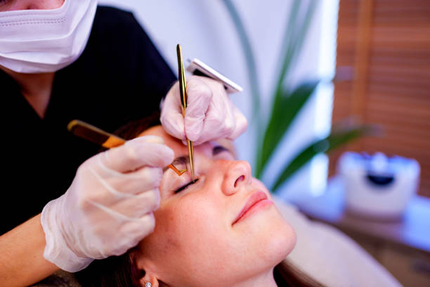istock A beautician applies artificial eyelashes to a client in a beauty salon with work tools in her hands 2184381725