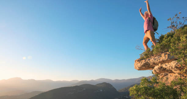 istock Mature man stands on cliff edge at sunset 2184390234